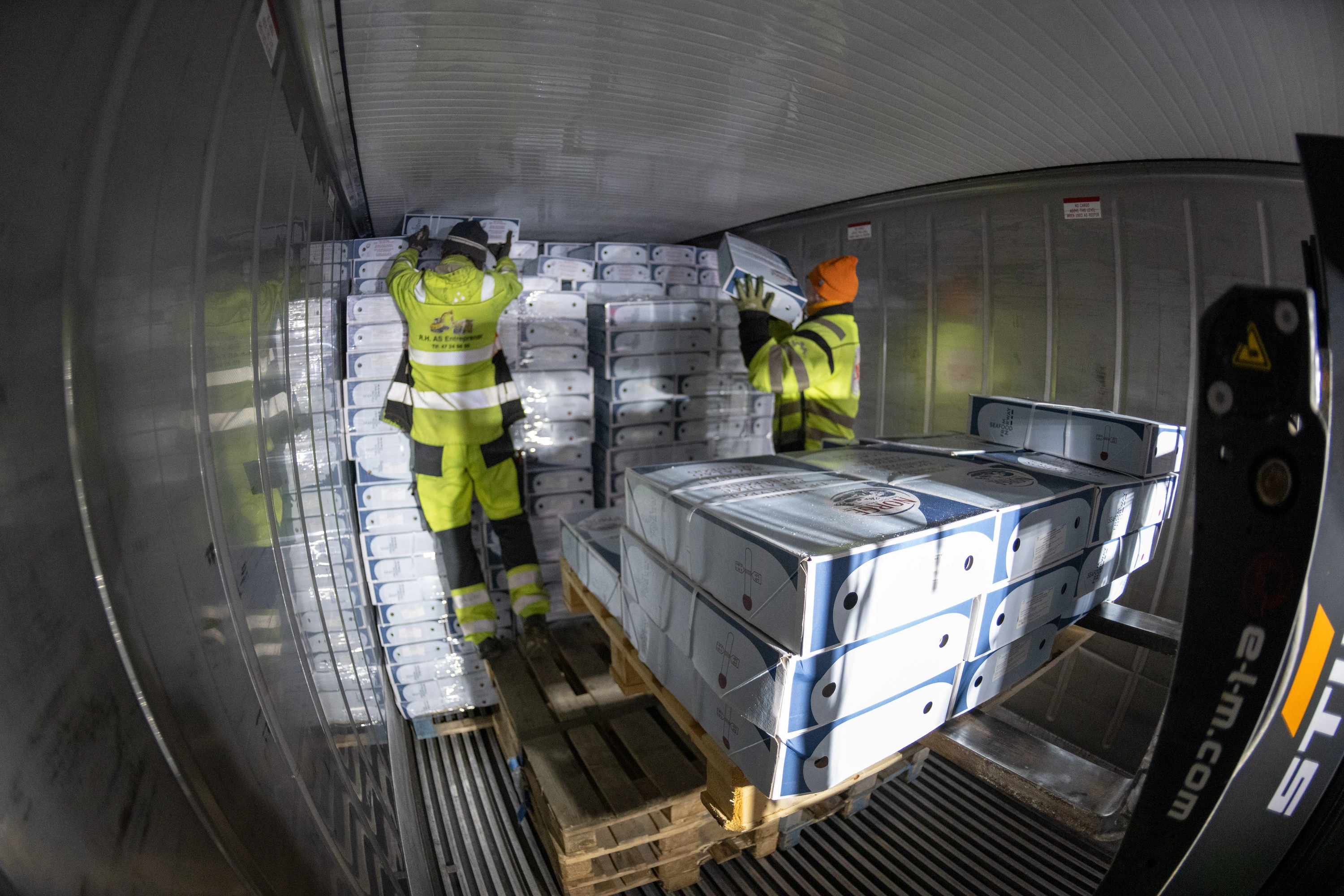 Warehouse workers and palletised goods inside a cold-storage room