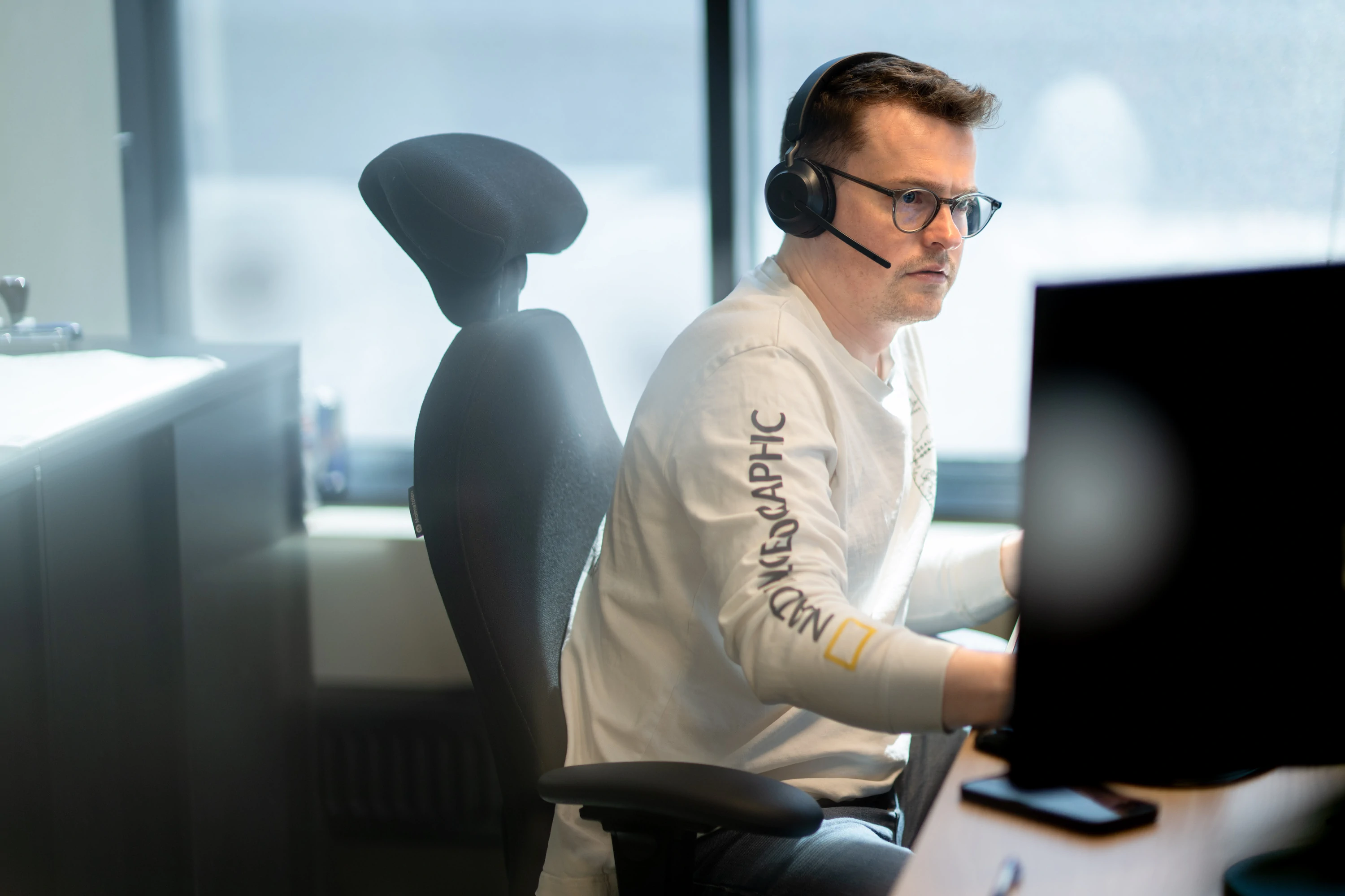 Medarbeider med hodesett ved datamaskinen
