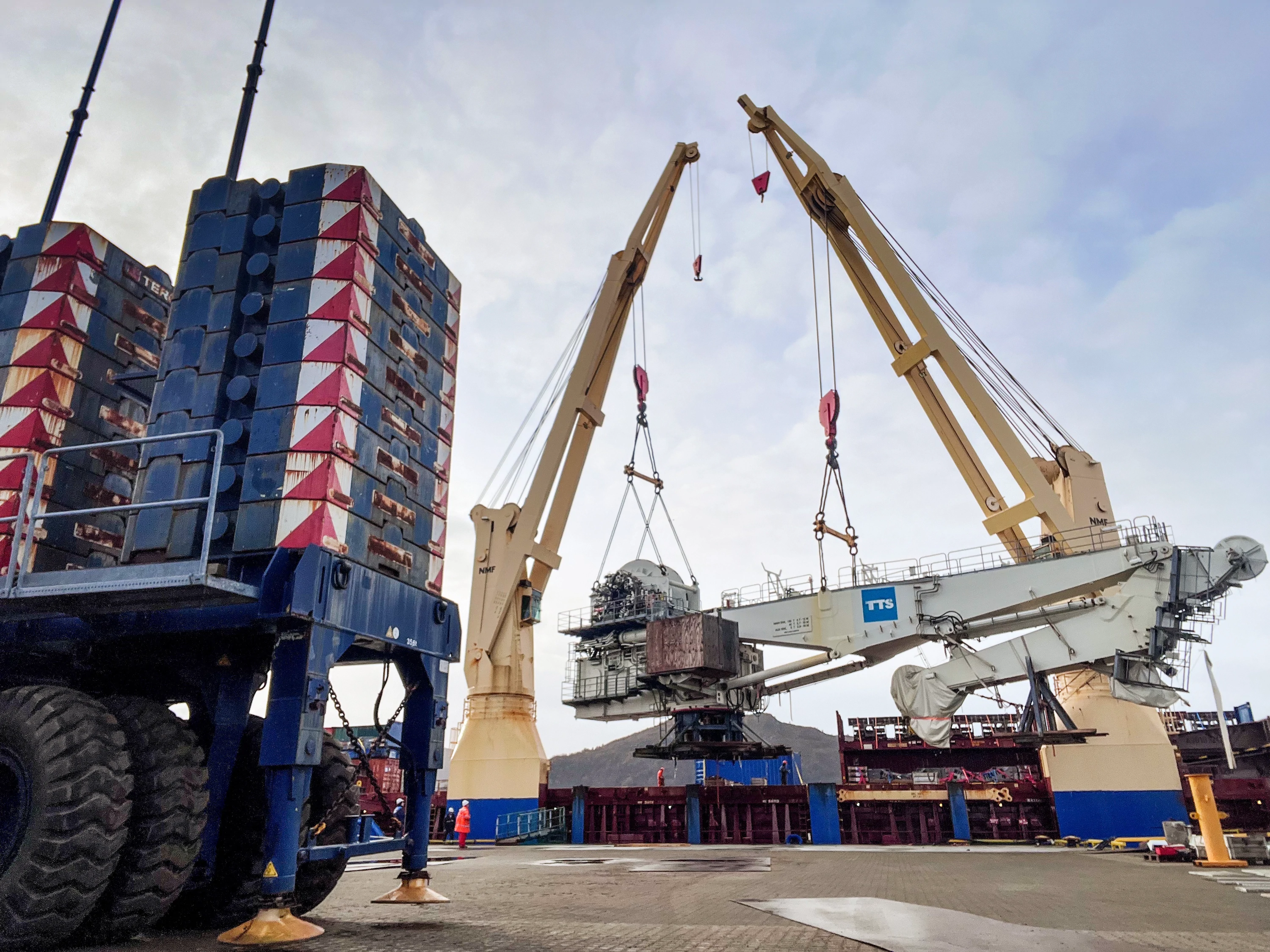 Ship cranes lifting heavy equipment aboard a vessel