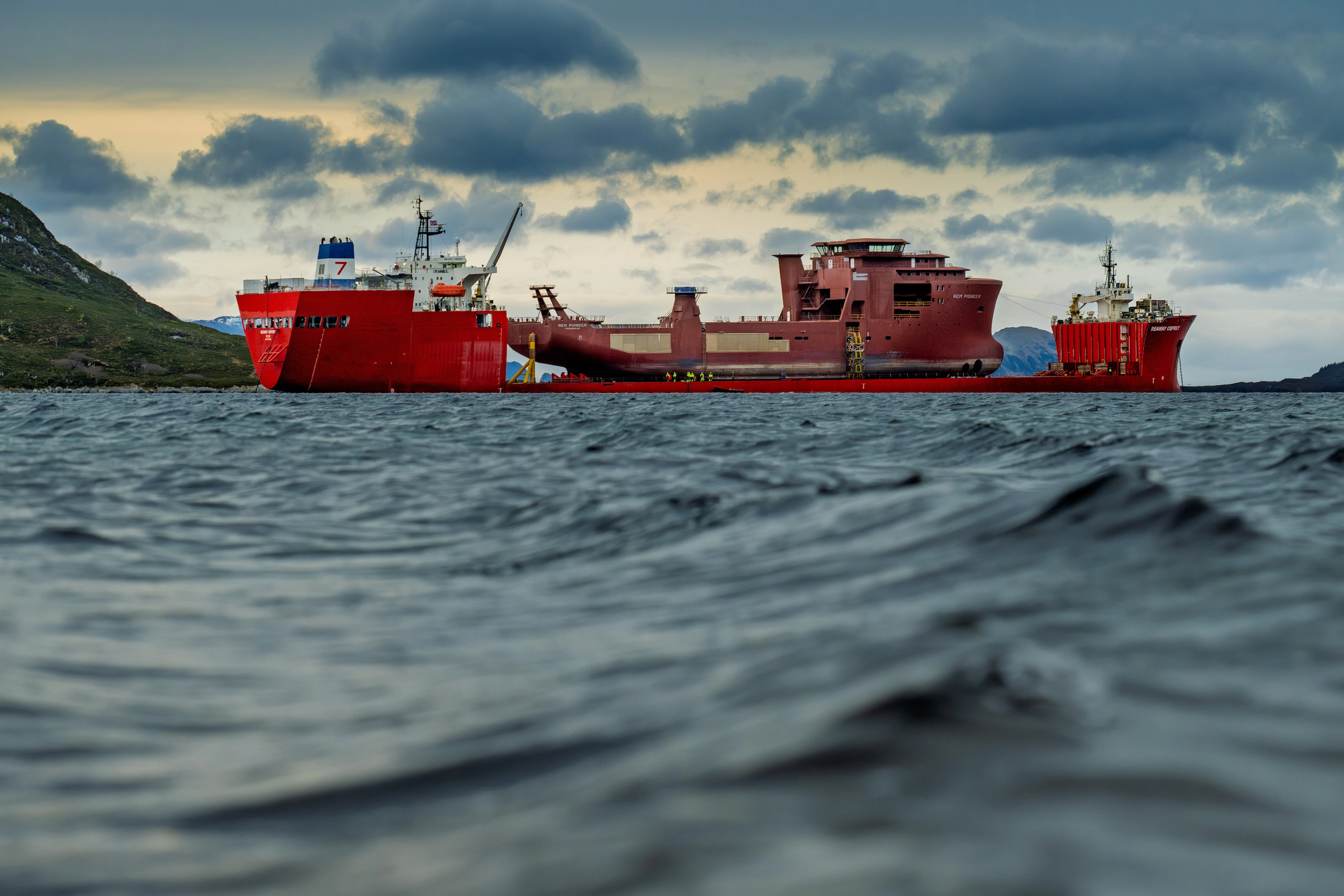 Red cargo ship sailing along the coast