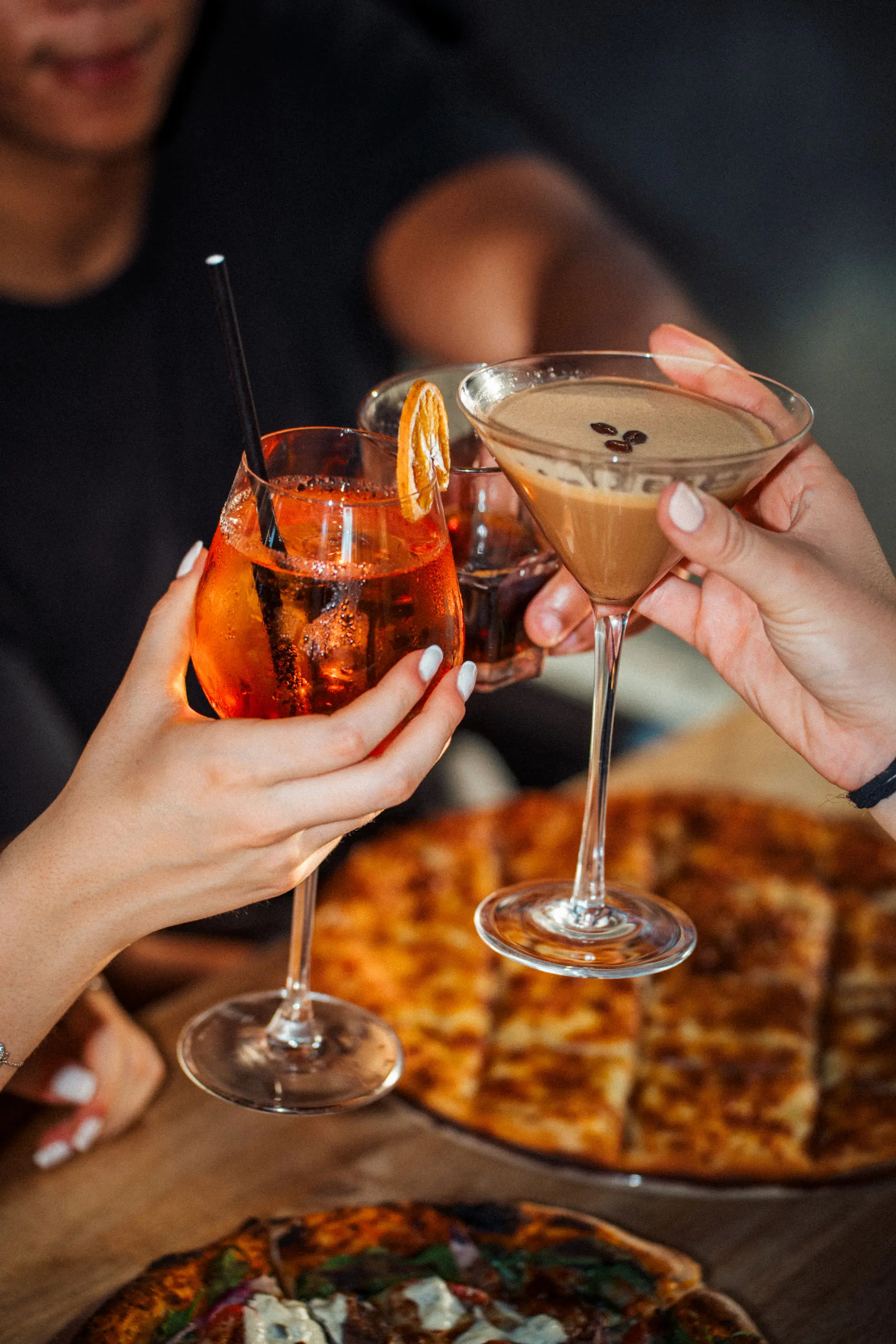 People cheering with drinks at functions and events in a restaurant, celebrating group dining experience.
