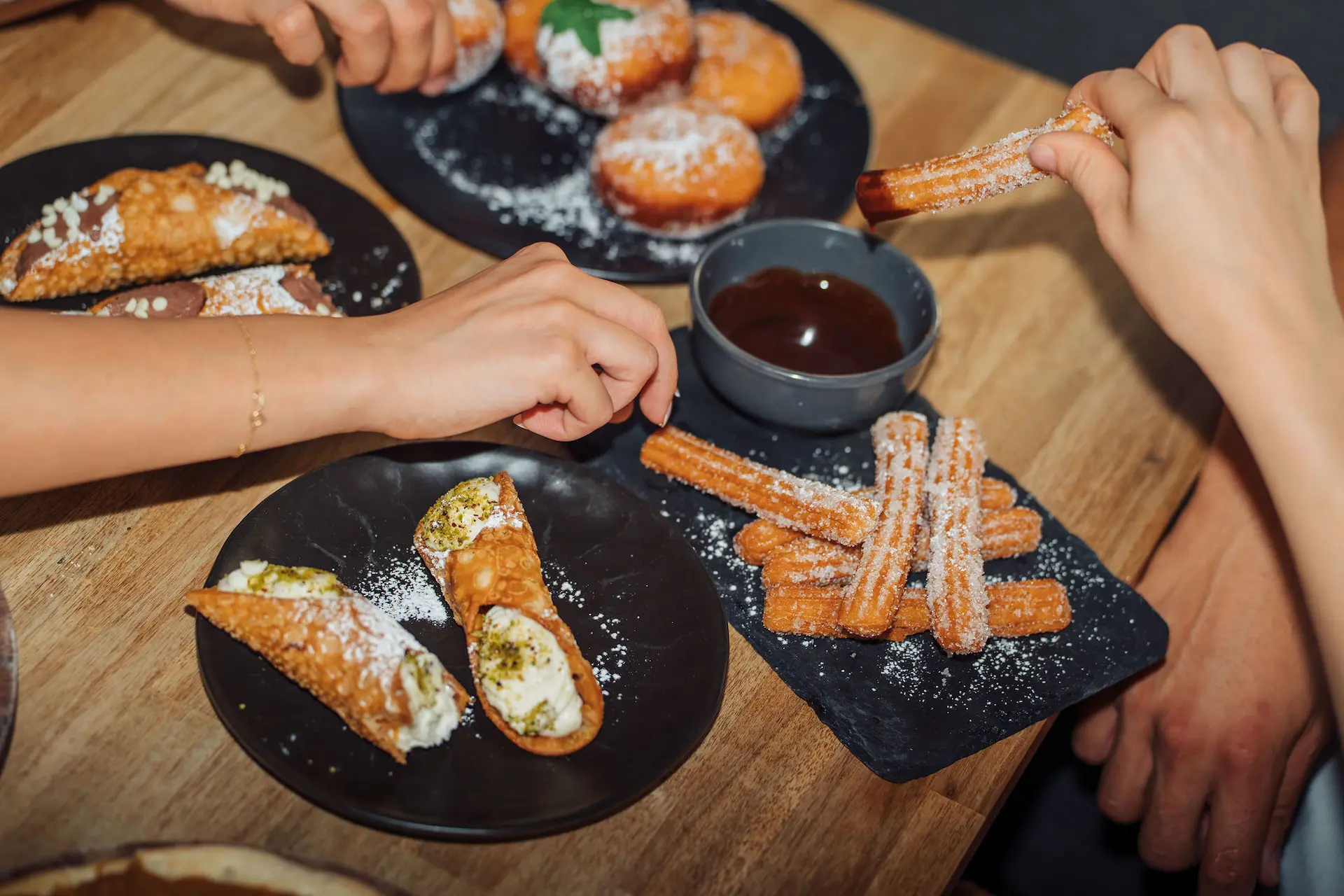 People sharing dessert in restaurant, enjoying food and social dining experience.