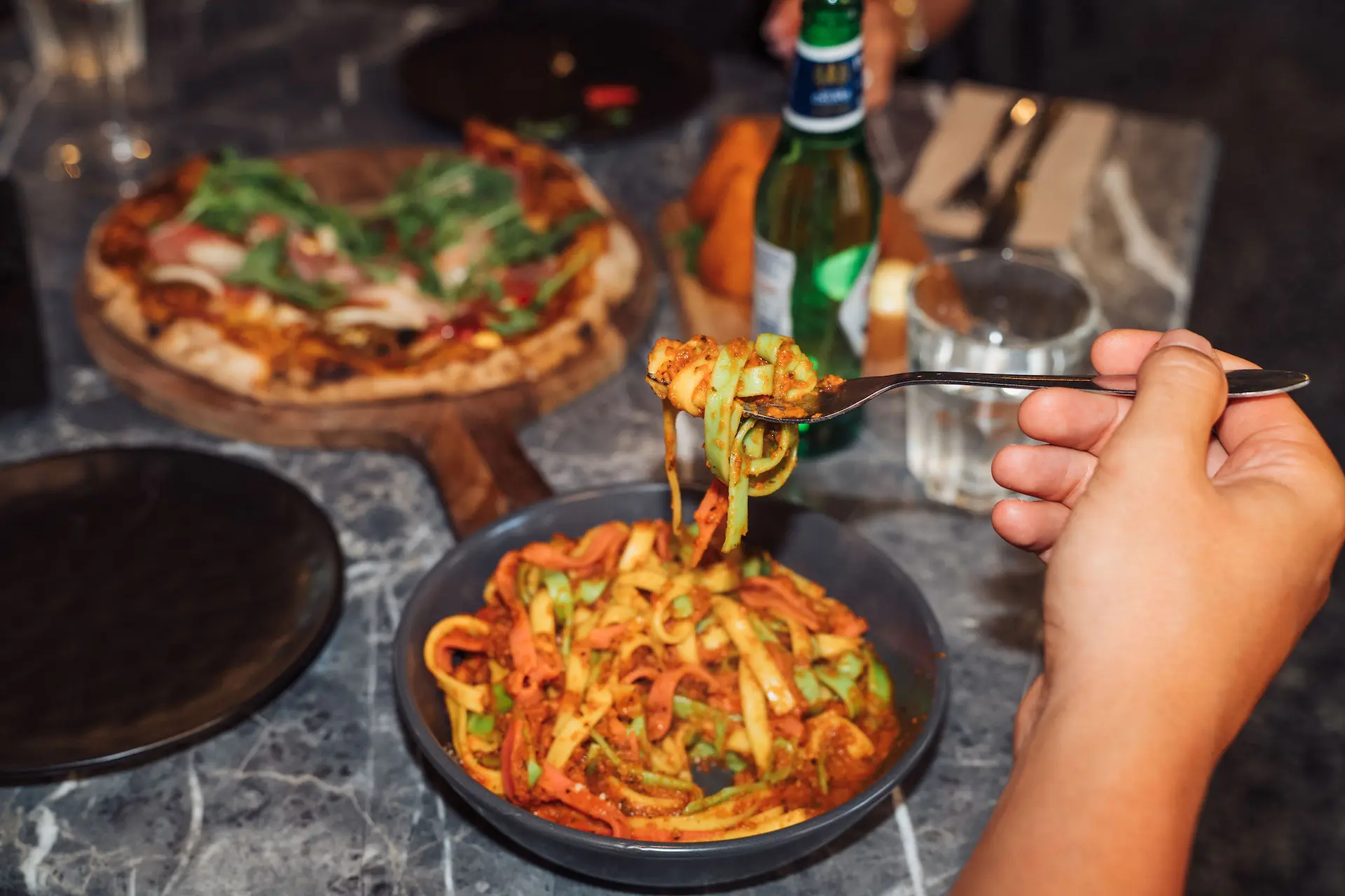 Person eating Italian pasta dish in restaurant, freshly made with authentic ingredients.