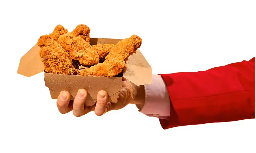 Hand in a red sleeve holding an open cardboard box filled with crispy fried chicken strips.