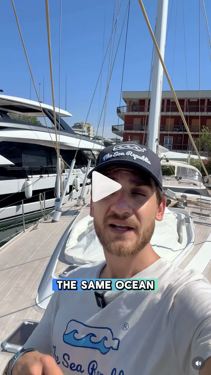 Uomo con cappello e maglietta 'The Sea Republic' su una barca a vela al porto.