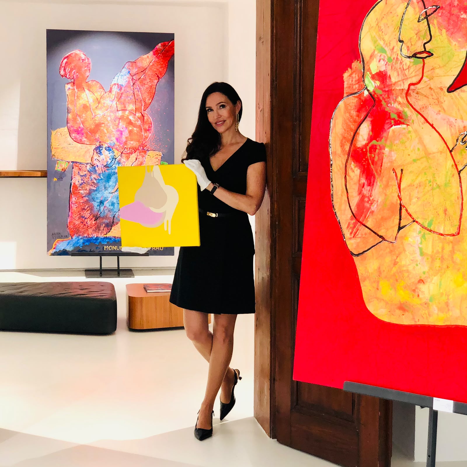 Petuscha Schopper im schwarzen Kleid hält kleines gelbes Gemälde in einem Raum der Park Galerie mit moderner Kunst an den Wänden.