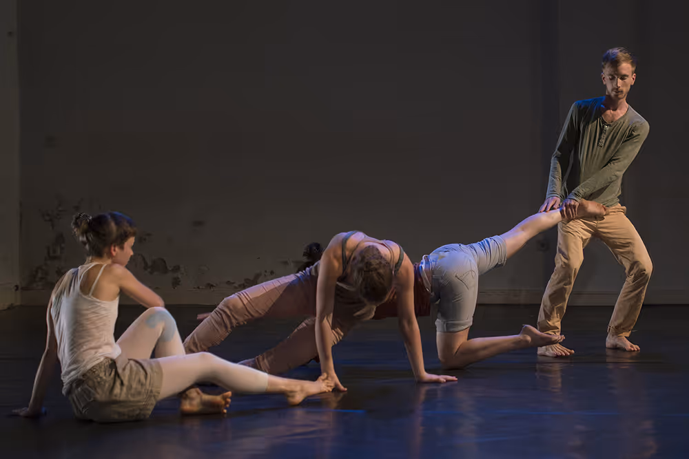 Ein Tänzer zieht einer Tänzerin auf der Bühne am Bein