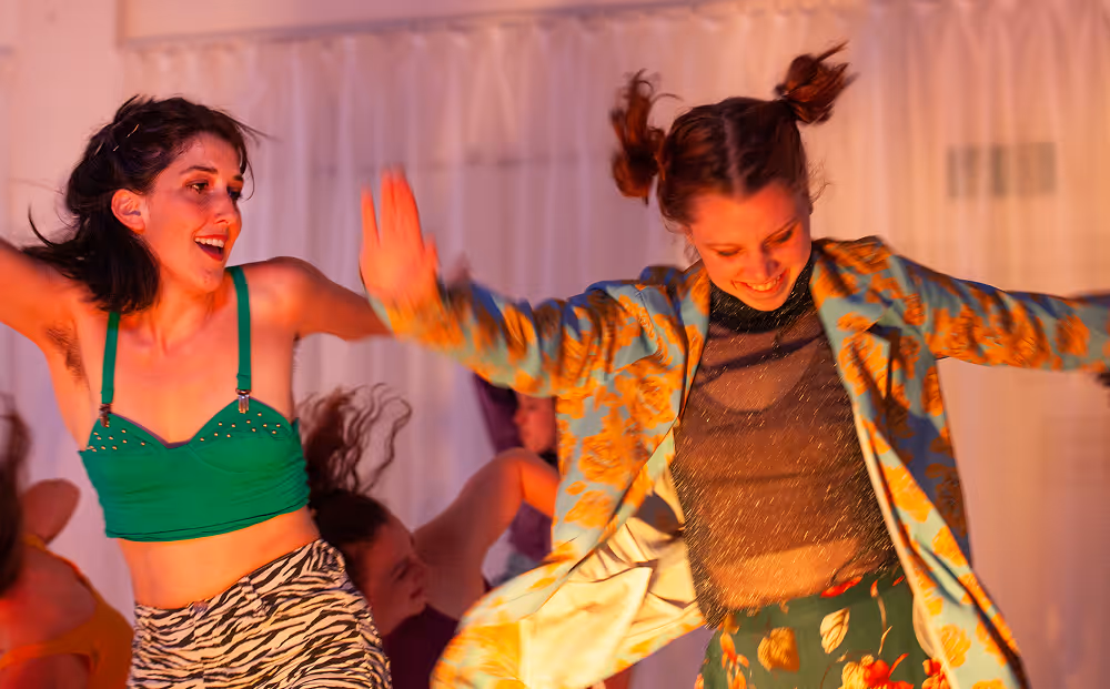 Zwei Frauen tanzen in farbenfrohen Kleidern auf der Bühne
