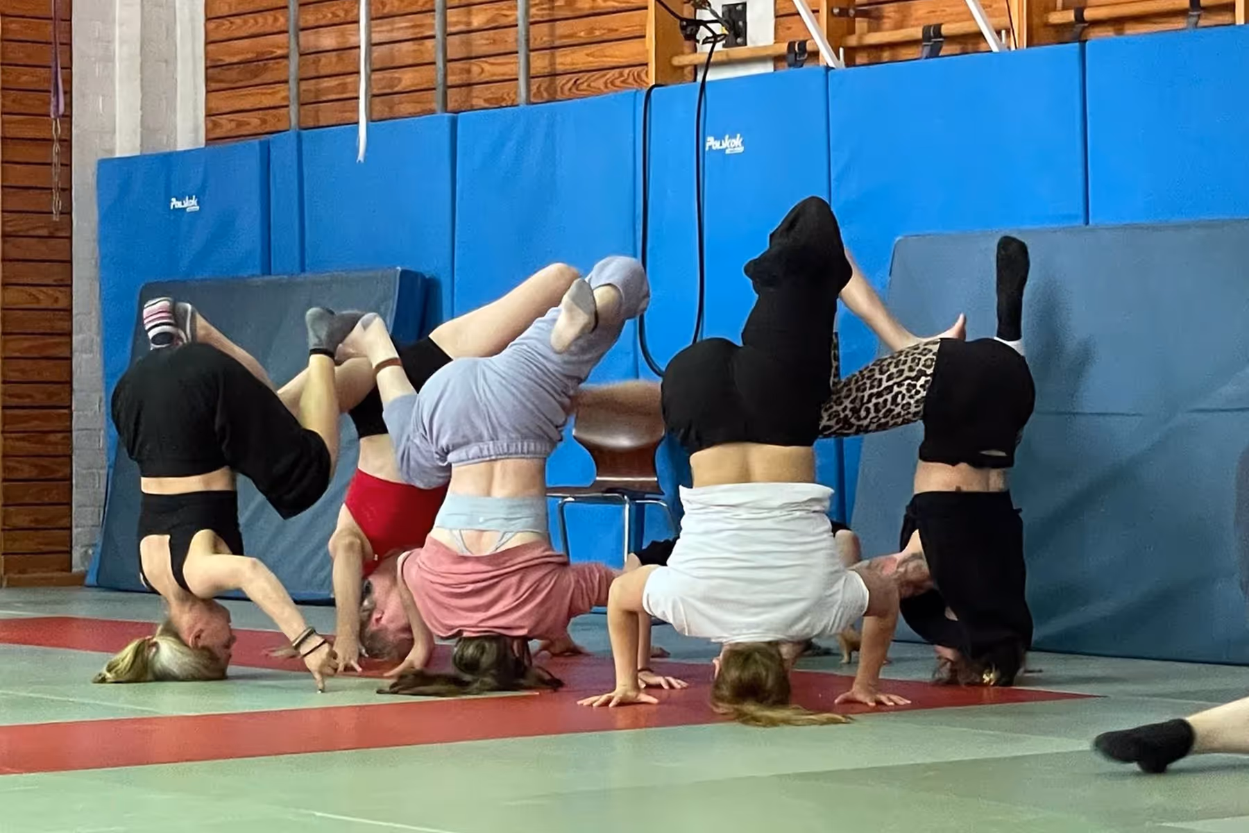 eine Gruppe von Menschen, die in einer Turnhalle einen Kopfstand machen