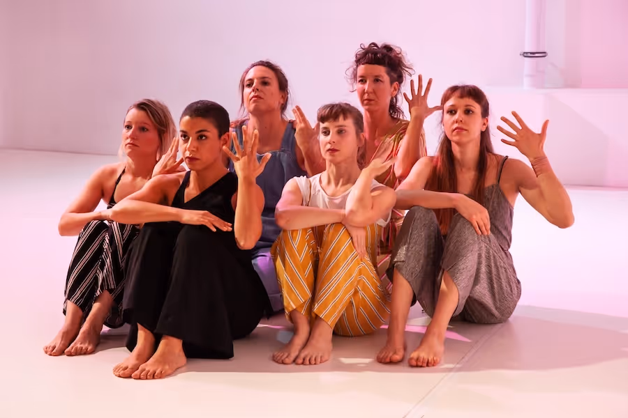 Tänzer, die mit erhobener Hand auf der Bühne sitzen