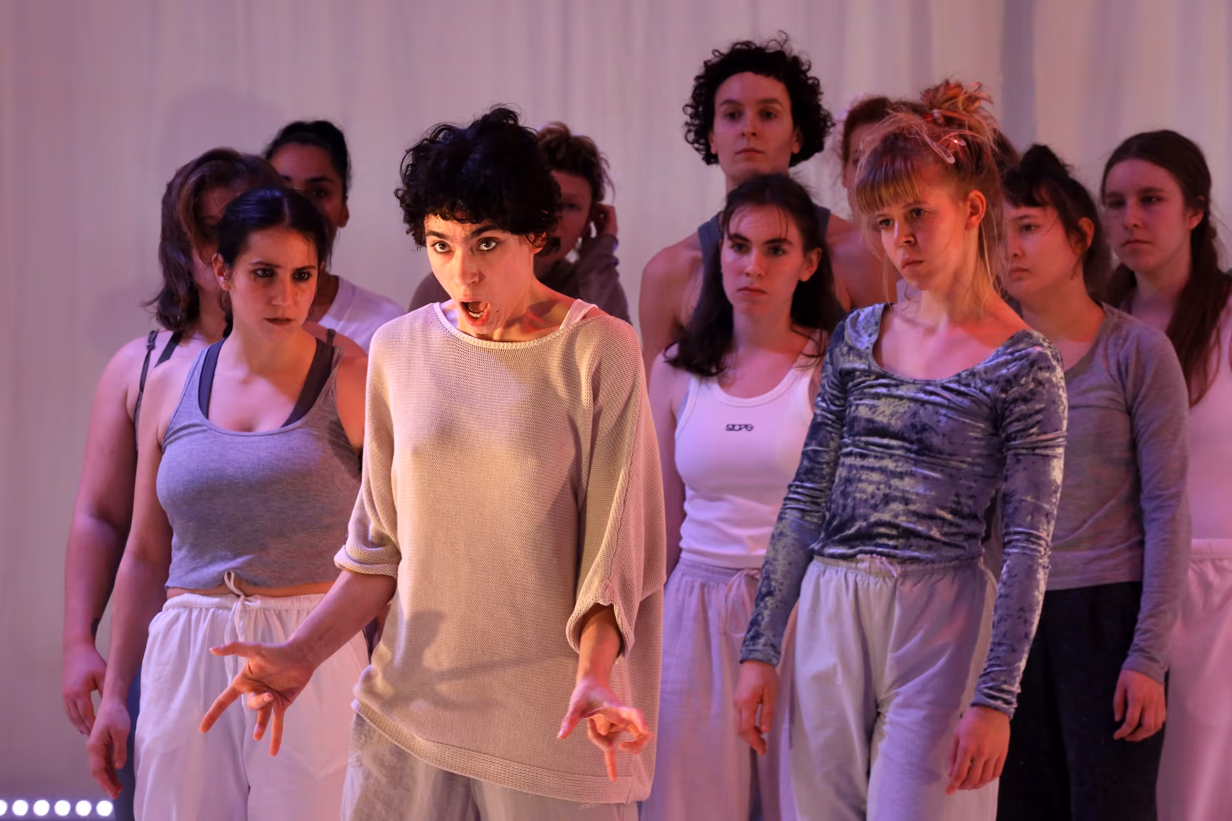 Eine Gruppe von Performern auf der Bühne. Eine Performerin ganz vorne singt