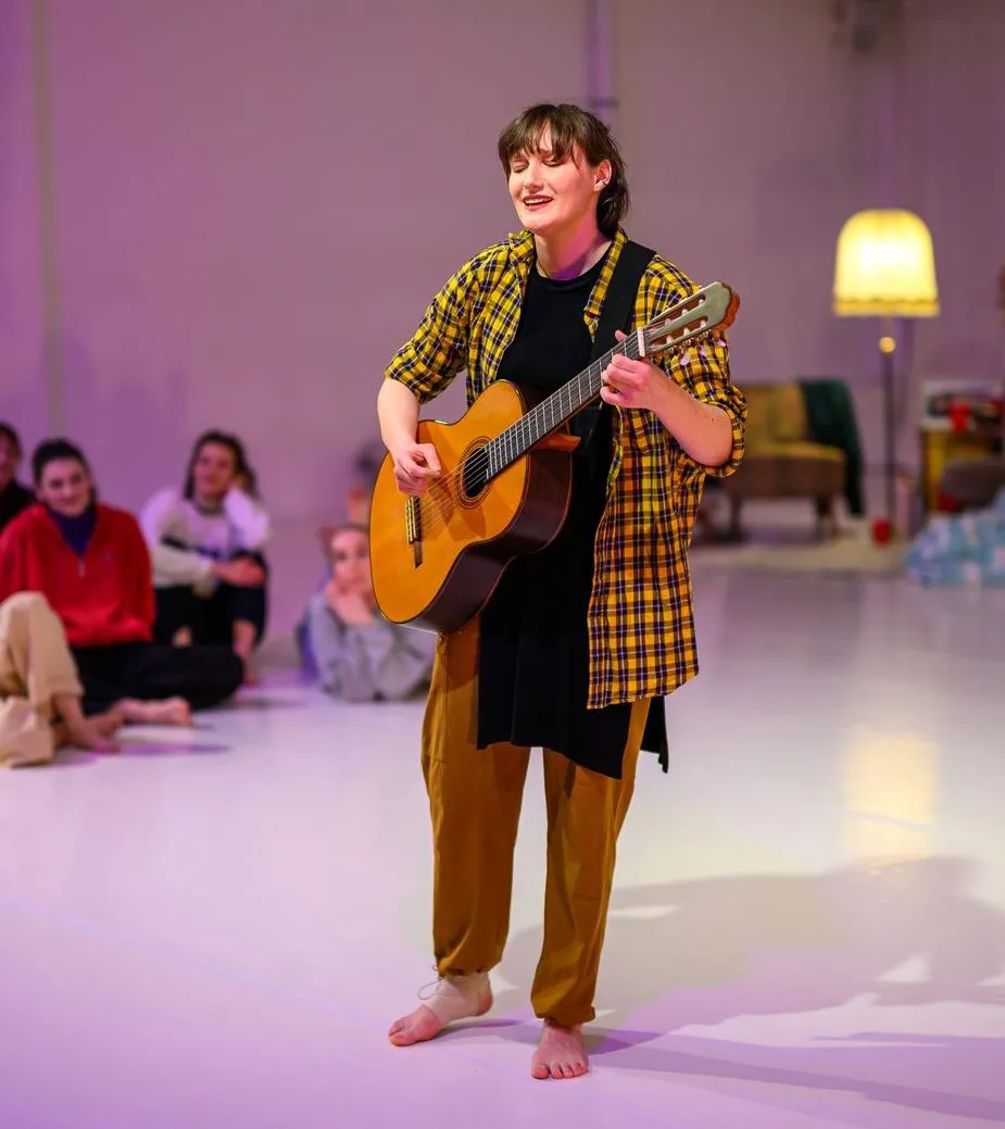 Eine Schauspielerin singt und spielt Gitarre auf der Bühne des Seneca Intensiv