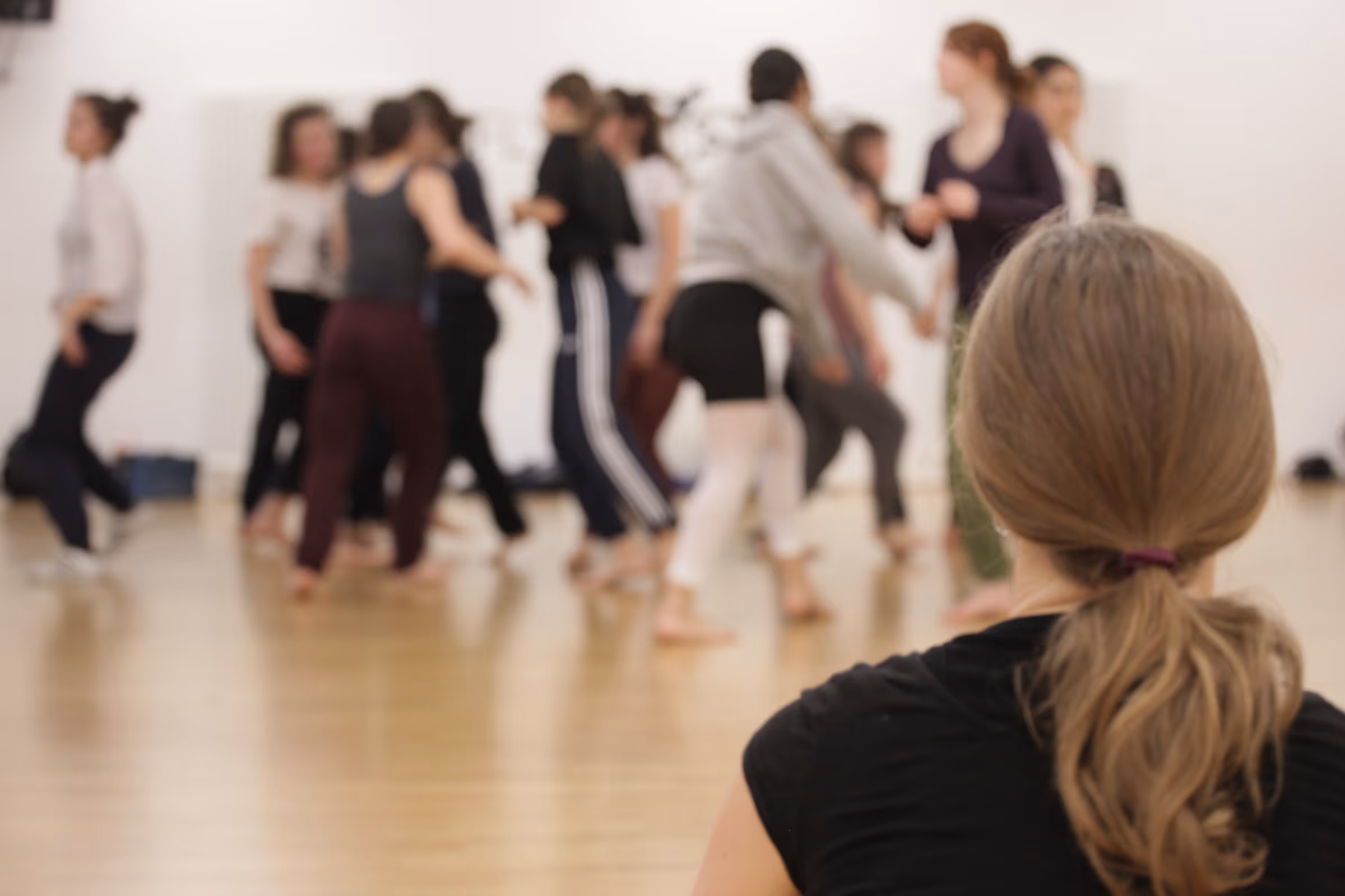 Eine Choreografin schaut Tänzern bei der Probe zu