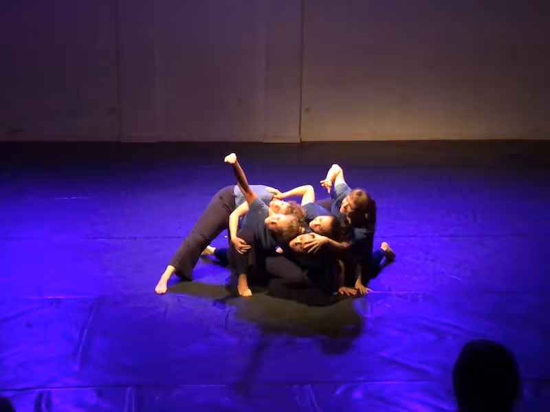 Tänzerinnen, die sich auf der Bühne zu einem Haufen zusammengekauert haben