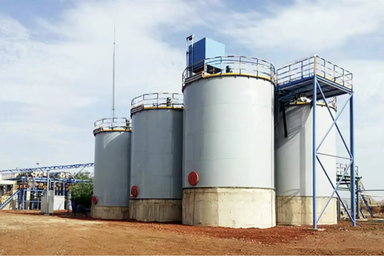 Group of large industrial storage tanks in an outdoor facility under a partly cloudy sky.
