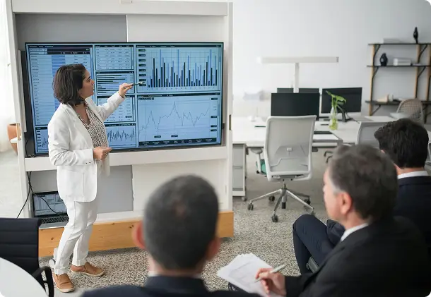 Presenter showing charts on a wall screen to colleagues in a meeting
