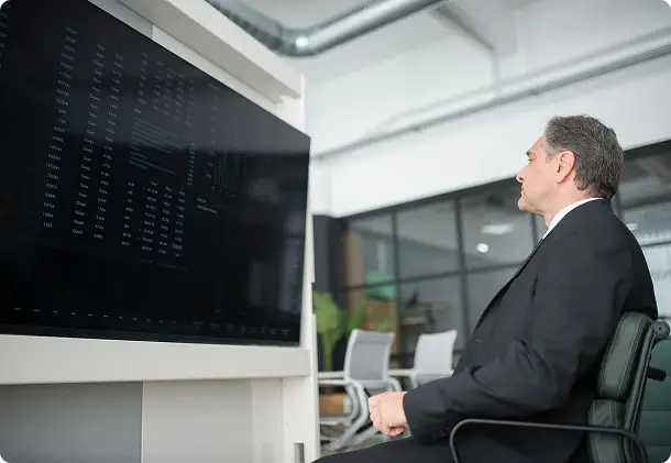 Executive looking at a large wall screen in a meeting room
