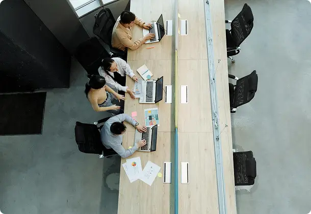 Overhead view of colleagues working at a long desk with laptops