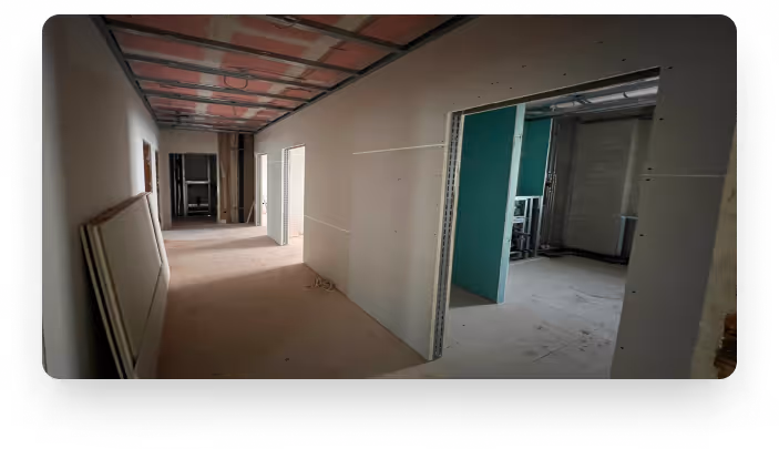 Flur im Rohbau eines Hauses mit unfertigen Wänden und Decke.