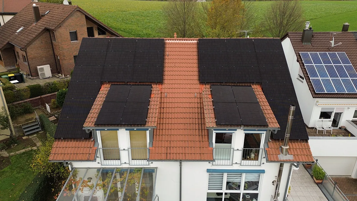 Ein Mehrfamilienhaus aus der Vogelperpektive. Auf dem roten Dach befinden sich Solarzellen.