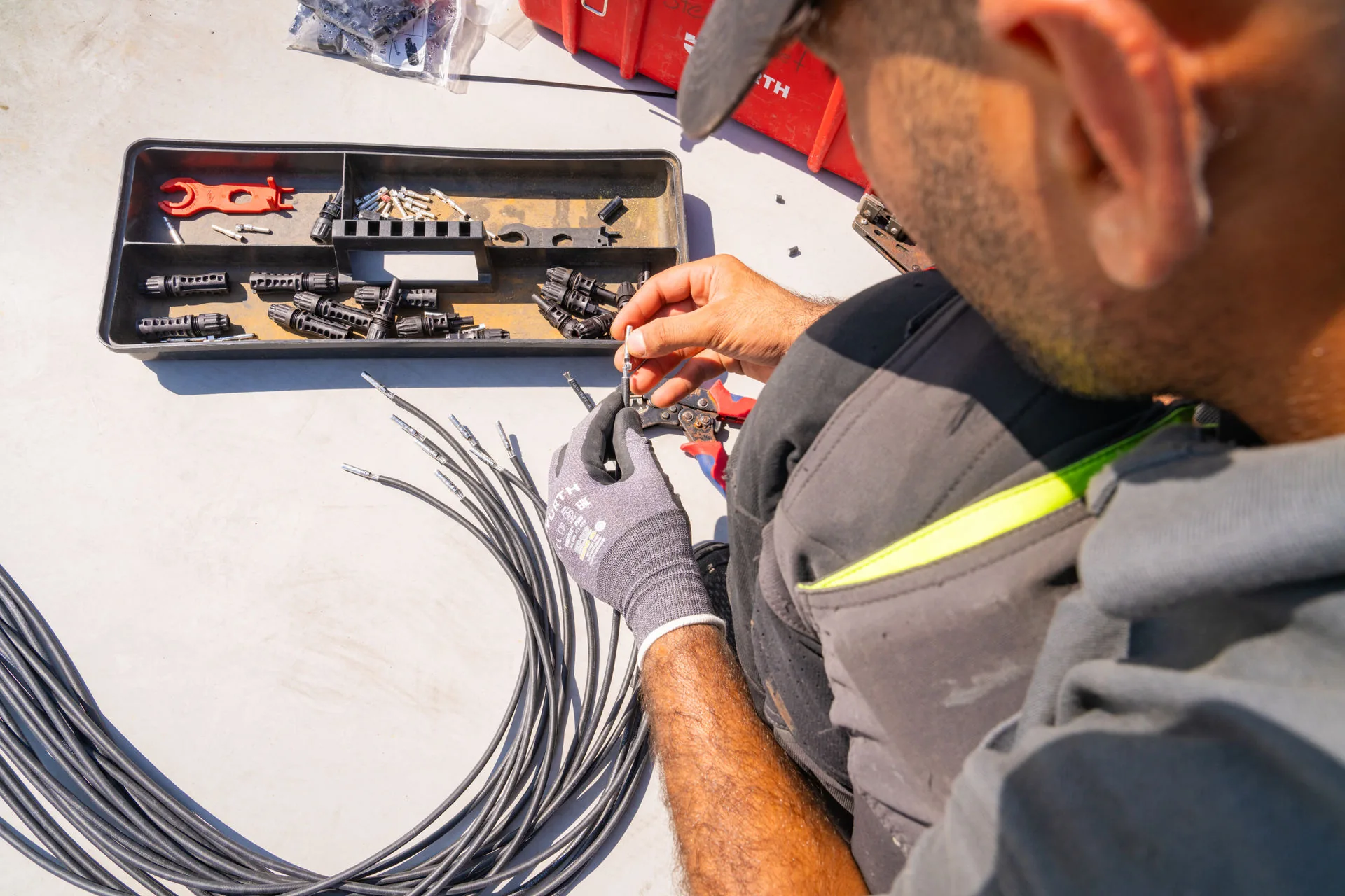 Ein Mitarbeiter von Reba Solar  wartet die Kabel einer Solaranlage und bringt neue Endhülsen an 