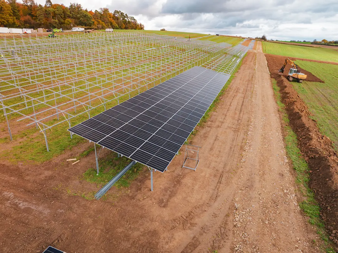 Eine Freifläche wird vorbeireitet für die Installation von einer großen Solaranlage. Teilweise sind Panele schon montiert, auf der restlichen Fläche steht das Grundgerüst