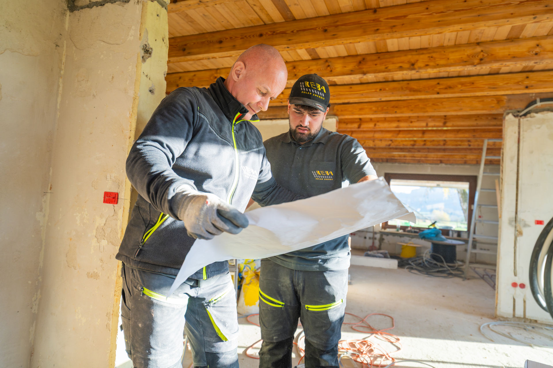 Das Team von Reba Solar schaut sich Grundrisspläne eines Neubaus auf einer Baustelle an, um die Installation der neuen Elemente zu planen. 