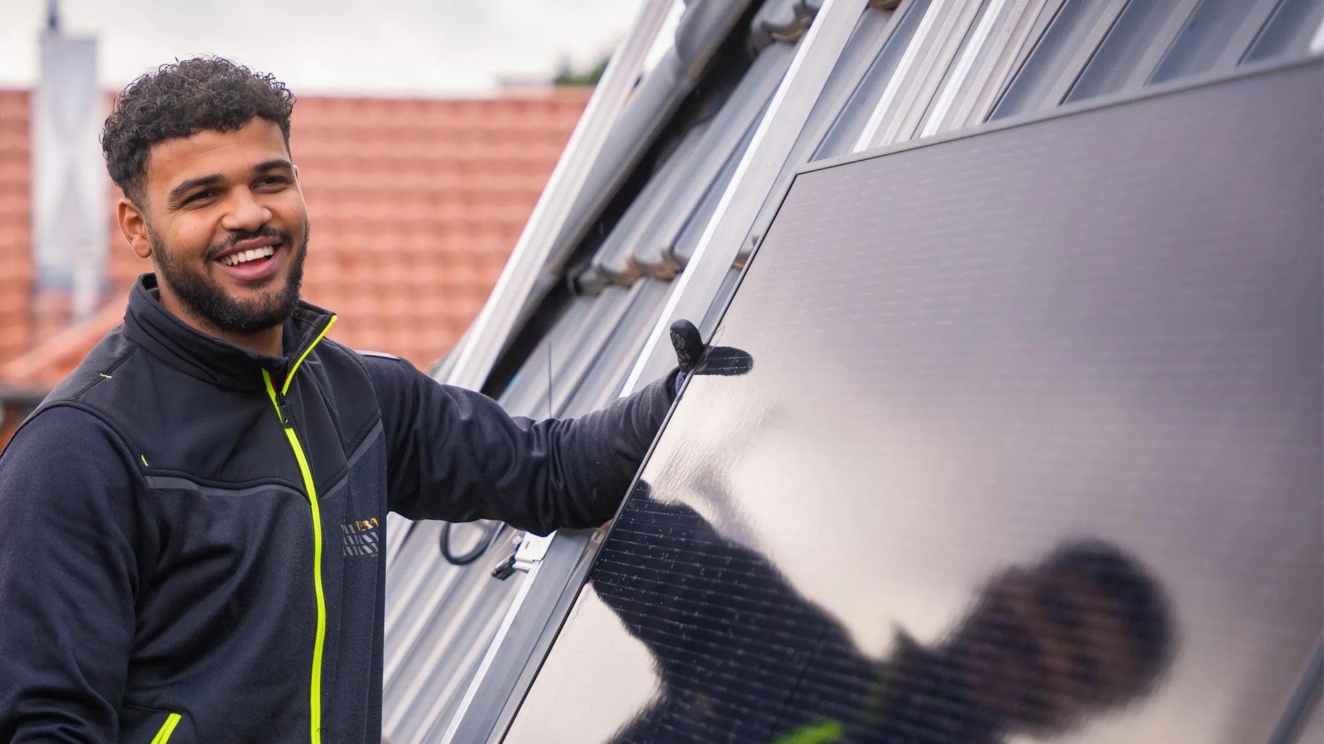 Ein Solarinstallateur mit einem Panele in der Hand, fertig zur Montage. 