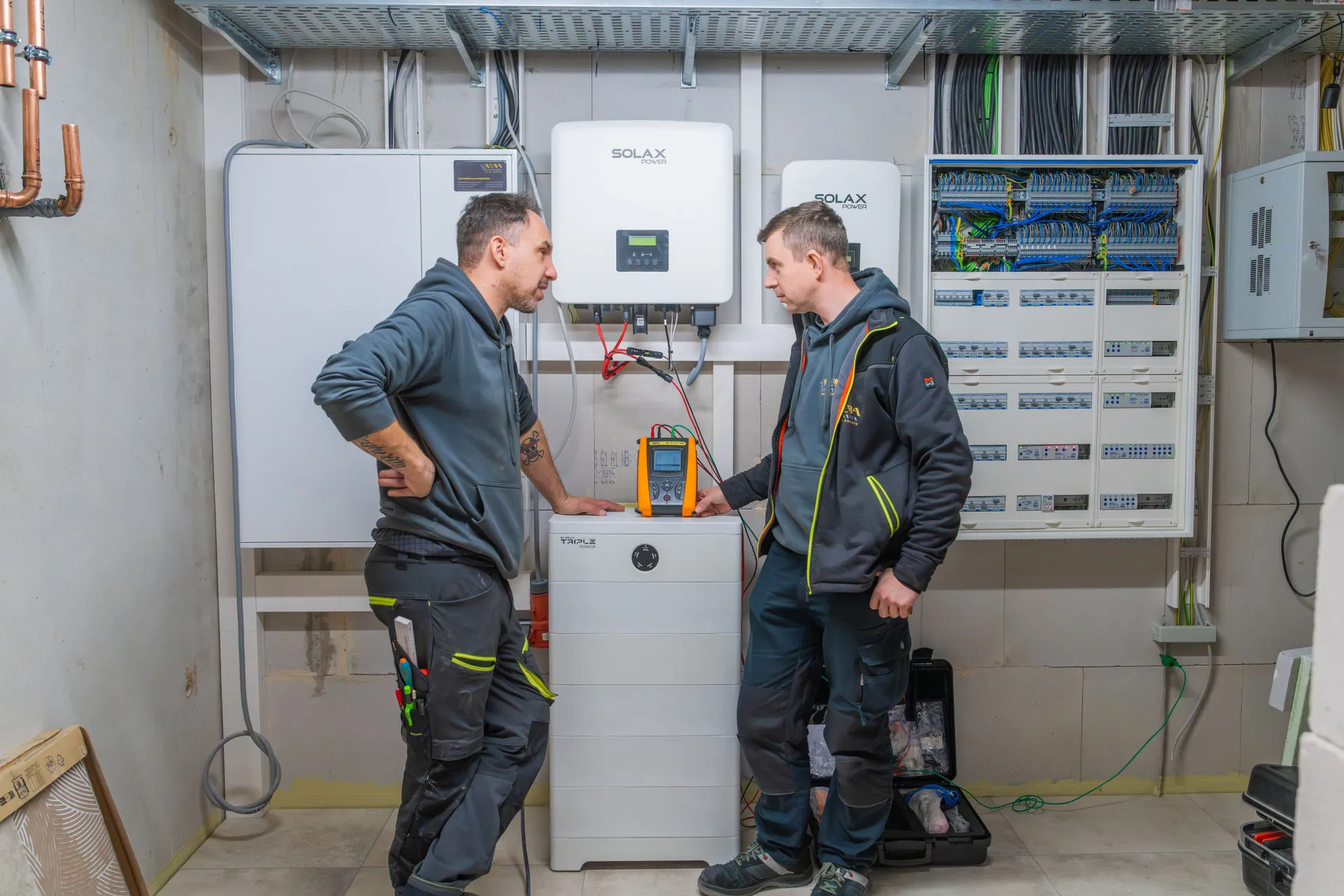 Fachkräfte bei der Wartung einer PV-Anlage mit SolaX Wechselrichtern und Batteriespeicher im Technikraum.