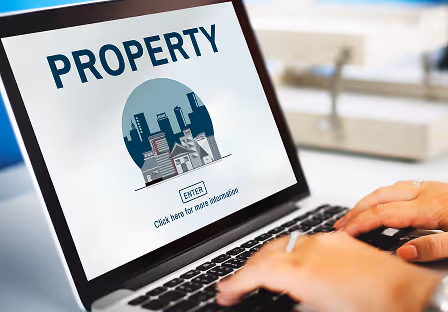 Person typing on a laptop showing a property access portal with an enter button and a city skyline graphic.