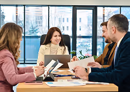 Four business professionals having a meeting around a table with documents and laptops in a bright office.