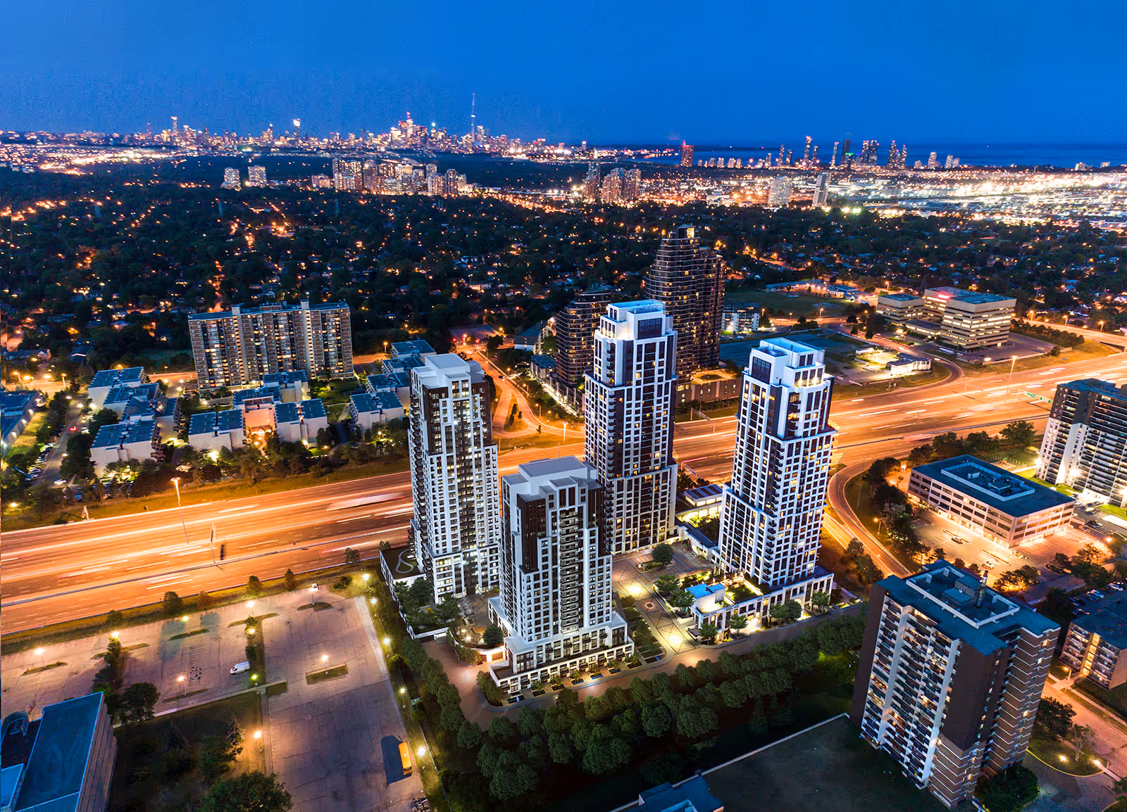 Aerial night view of a modern urban cityscape with illuminated high-rise buildings and busy highways.