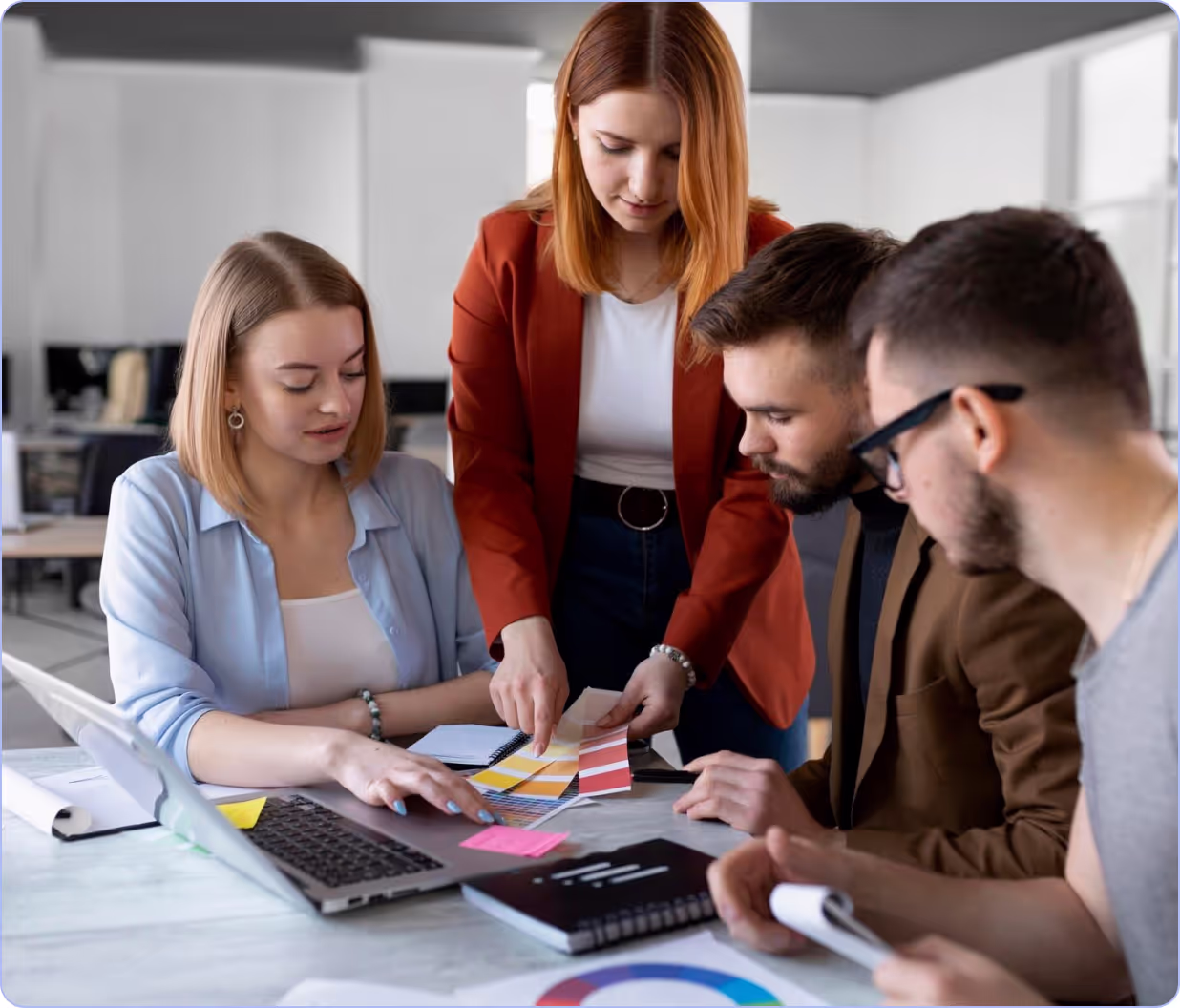 A group of people standing around a laptop computer.