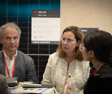 Three professionals engaged in a discussion at a table with documents in front of them.