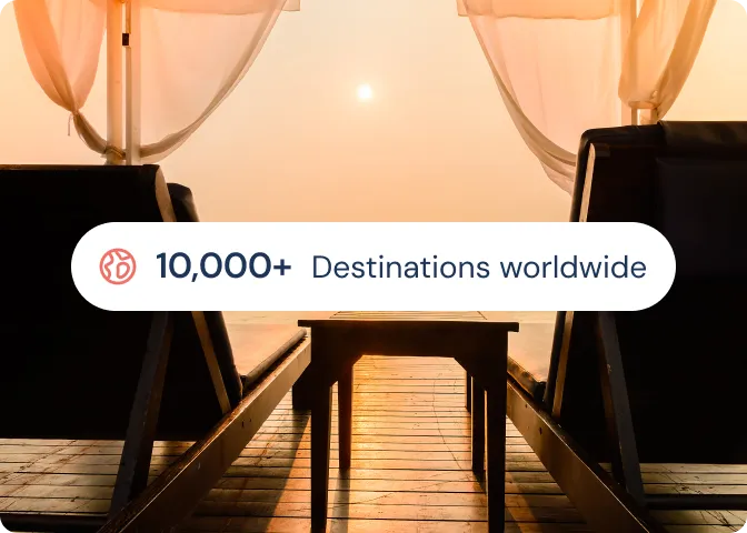 Two lounge chairs facing a setting sun with a wooden deck and text stating '10,000+ Destinations worldwide'.