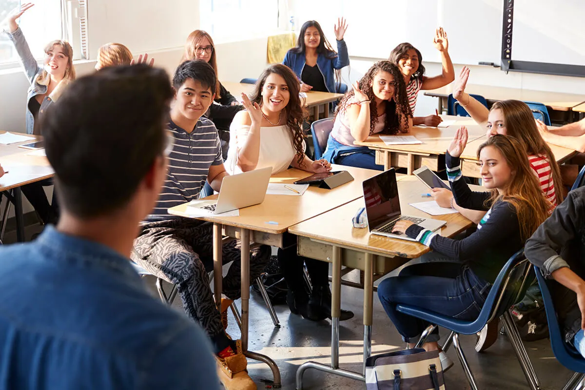 Students raising hands in classroom