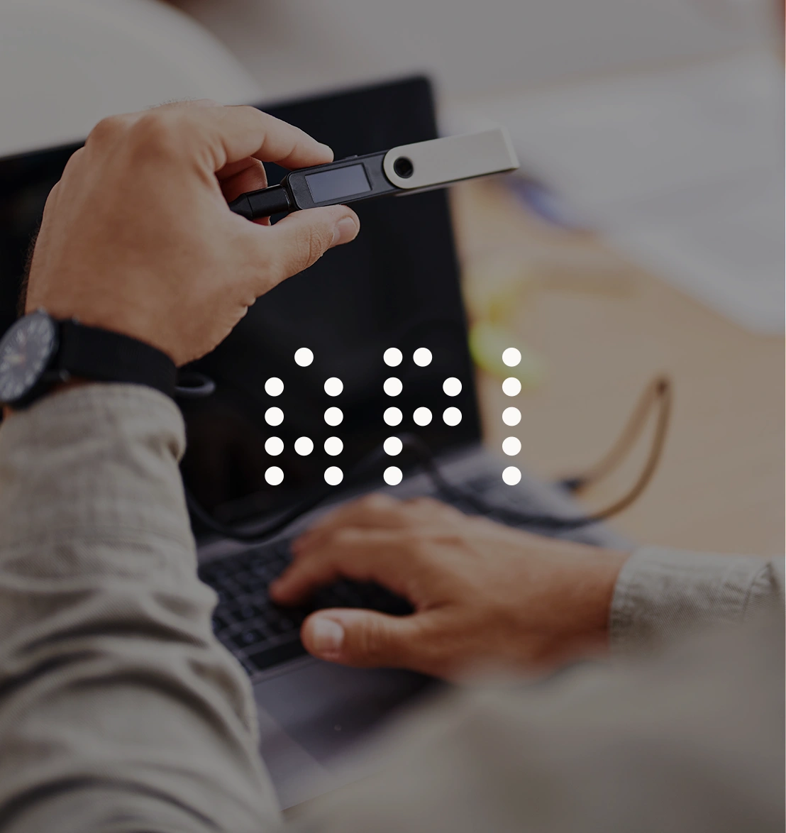 Developer holding a hardware crypto wallet while working on a laptop, with an API icon overlay