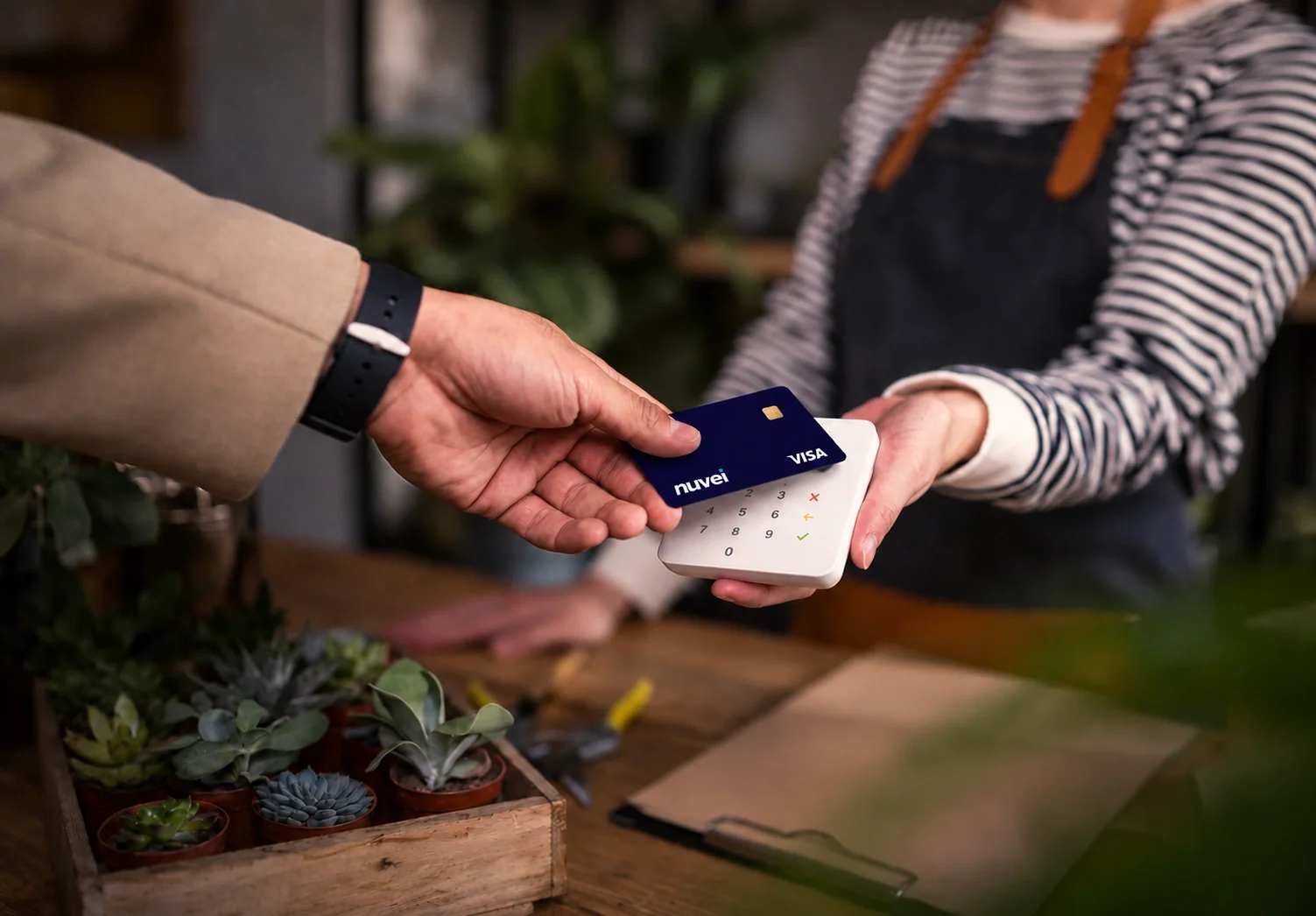 An image of two people in a payment transaction: one behind the counter and the client using contactless technology. 