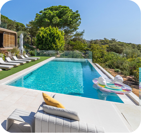 Piscine extérieure avec des transats blancs, un matelas gonflable coloré dans l'eau, entourée d'arbres et de végétation.