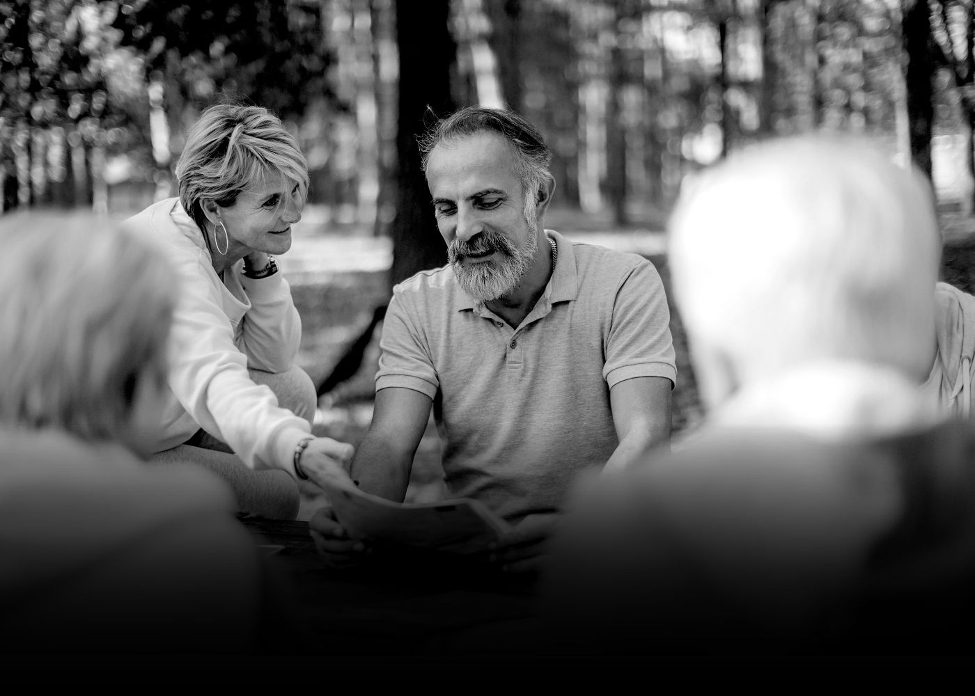 Three hikers standing on rocky terrain overlooking a foggy mountainous valley, one person pointing into the distance.