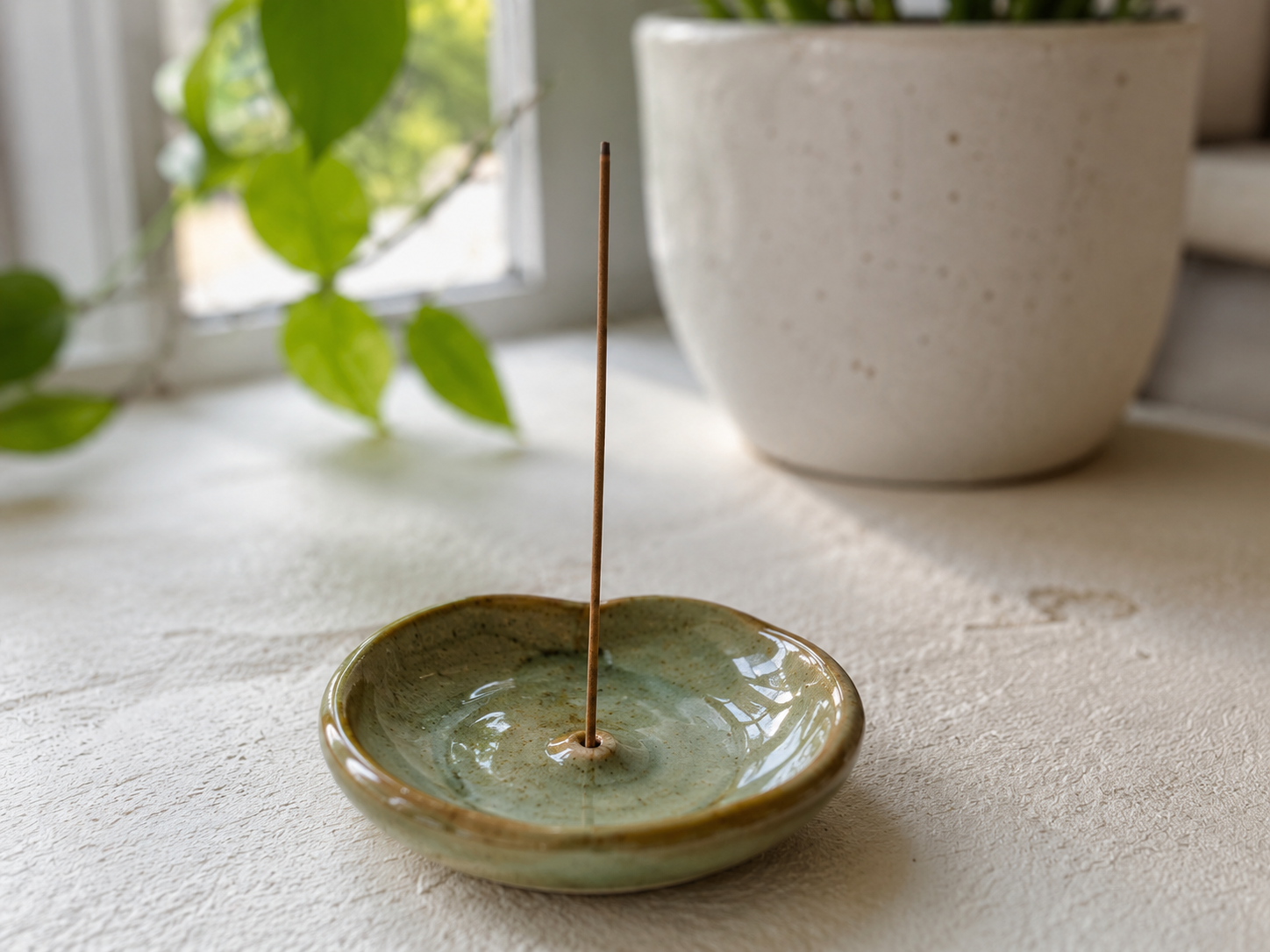 Pieza hecha a mano en barro, con una forma baja y cómoda para dejar ceniza o una varilla de incienso. El borde quedó ligeramente irregular, que le da ese punto artesanal sin complicarse. Después se esmaltó en verde, dejando pequeñas motas y brillos que hacen que parezca usada y lista para estar en cualquier rincón de casa.