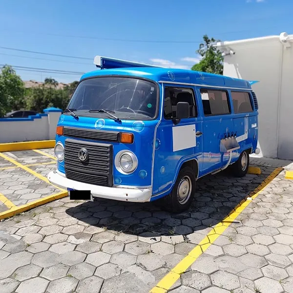Van azul da Volkswagen estacionada ao ar livre em vaga demarcada com linhas amarelas.