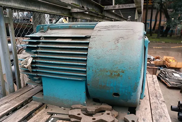 Motor azul enferrujado colocado sobre uma superfície de madeira ao ar livre.