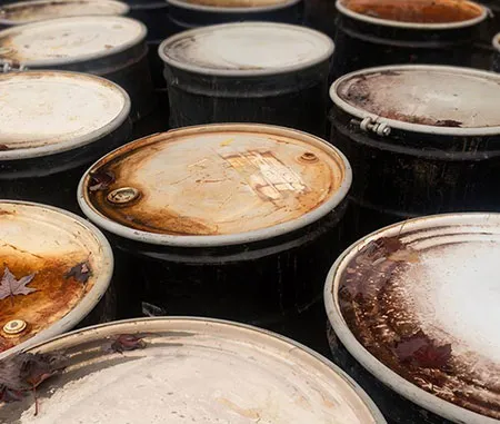 Tampas enferrujadas de tambores pretos armazenados lado a lado.