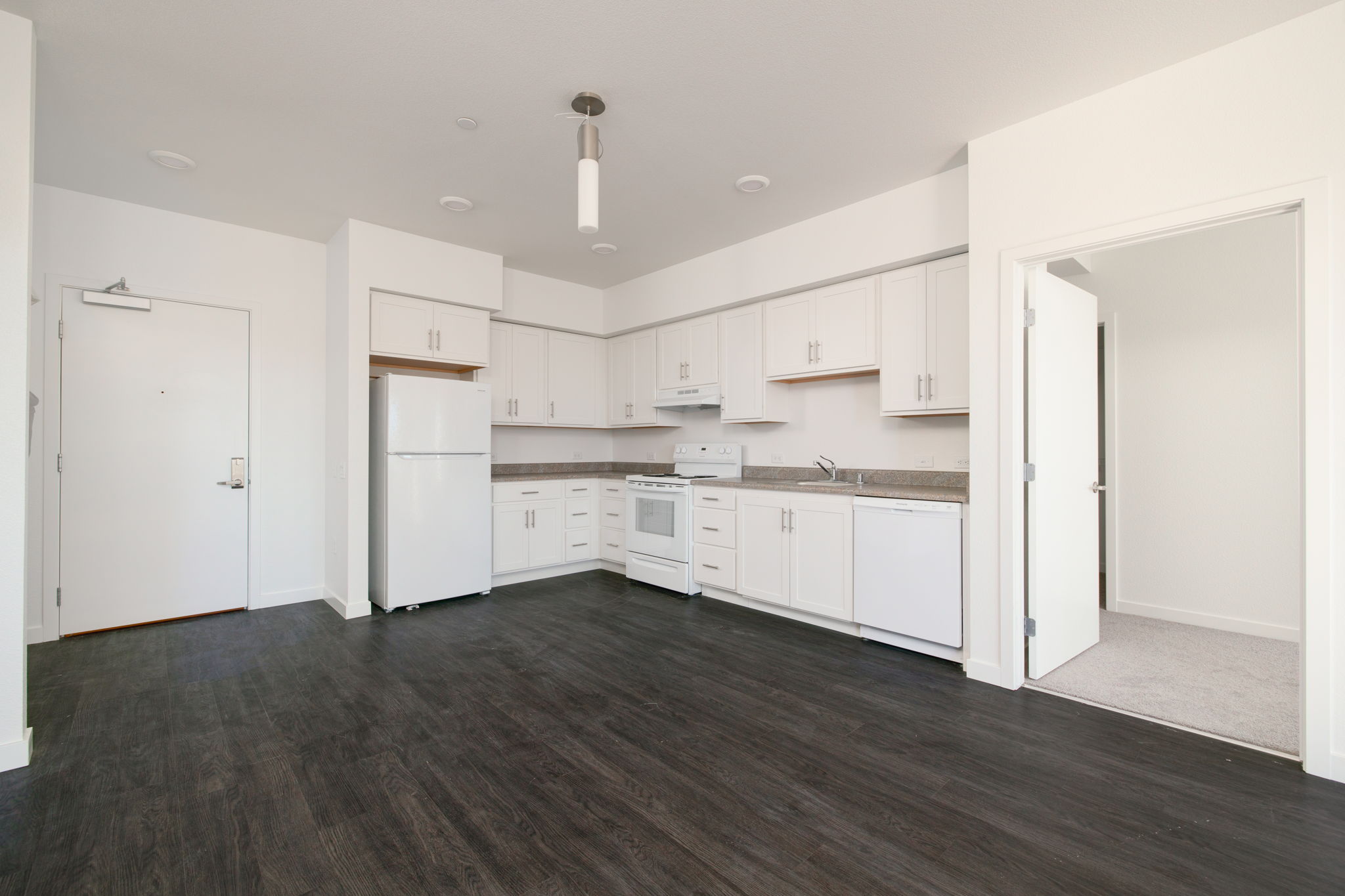 View of living area unfurnished and kitchen with white cabinets and white appliances