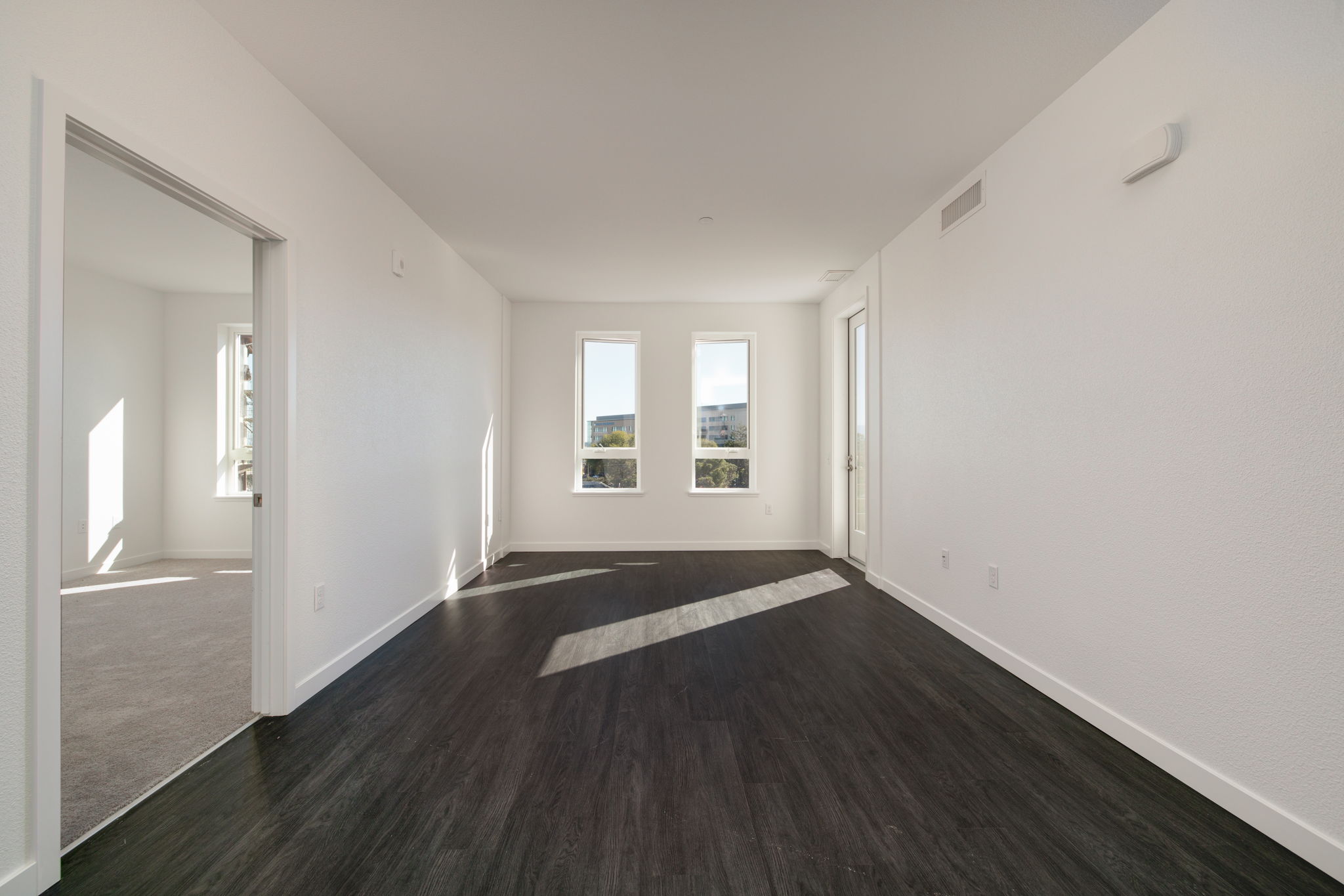 View of living area unfurnished with large windows and wood floors