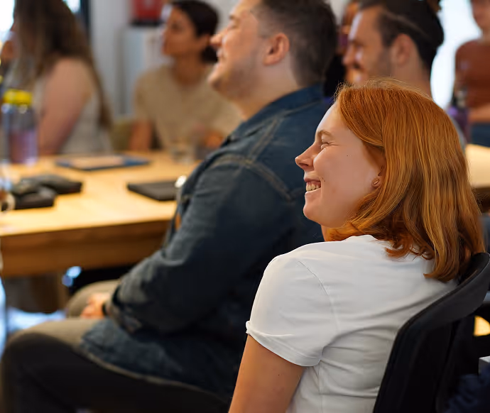 Menschen sitzen in einem Meetingraum und lachen während einer Besprechung.