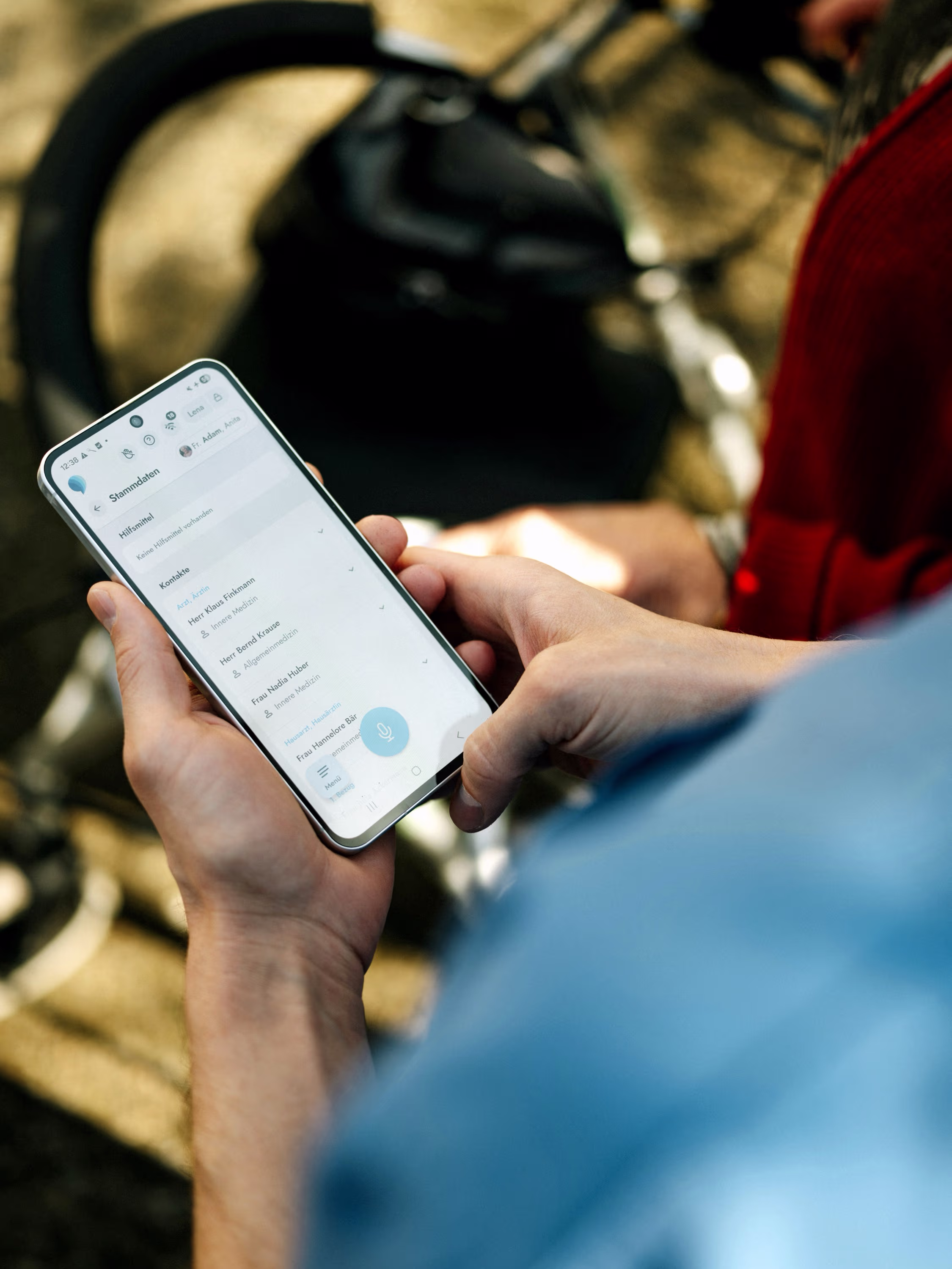 Person hält ein Smartphone mit einer geöffneten Kontaktliste mit Ärzten in deutscher Sprache.