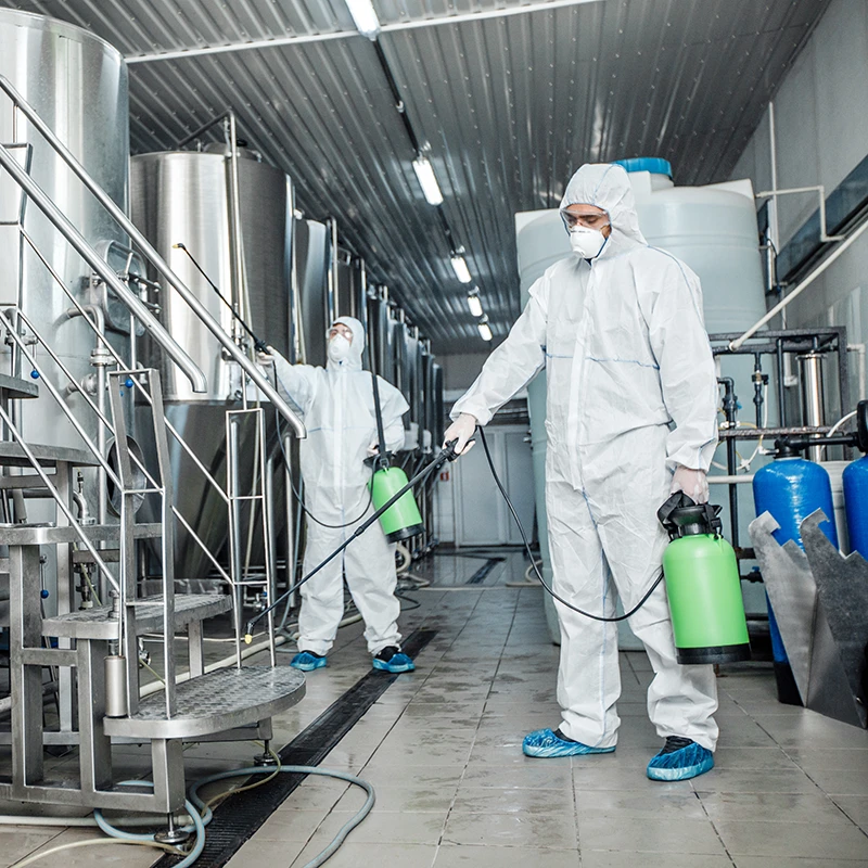 Des professionnels en combinaison désinfectent une usine