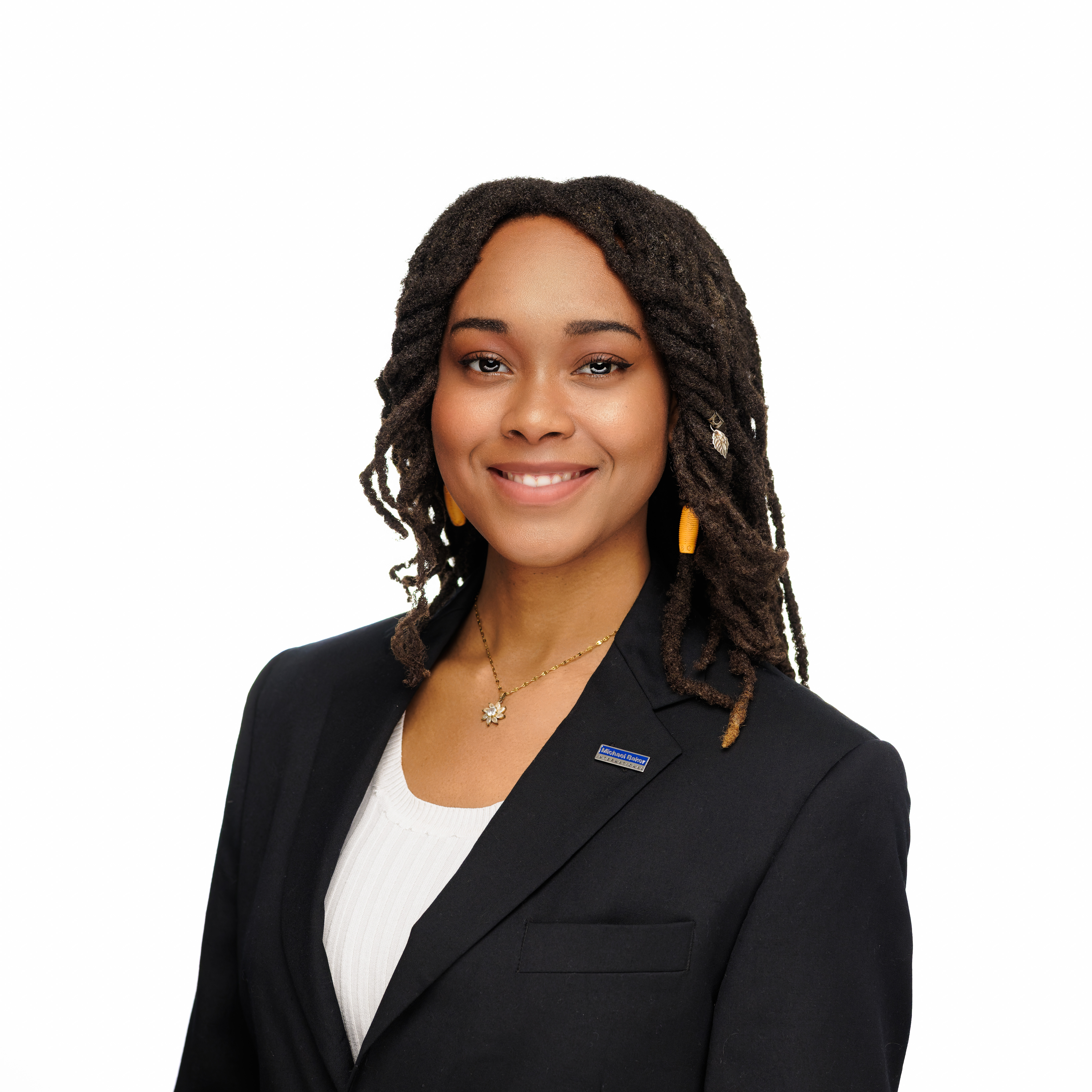 Young woman with braided hair and yellow earrings smiling in a black blazer and white top.